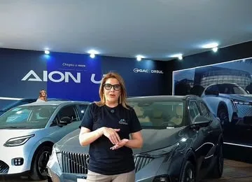 Interior do estande AION e GAC DRSUL, com carros expostos, teto fechado e piso de deck.