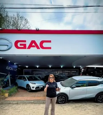 Estande GAC visto de fora, com testeira branca e vermelha e carros na área externa.