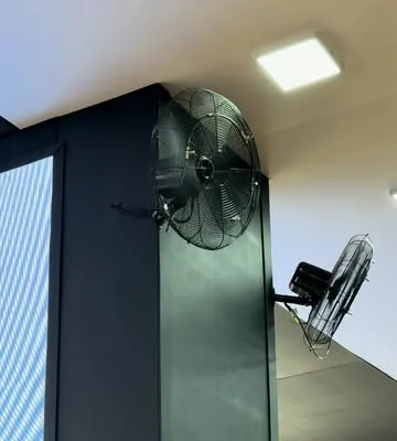 Ventiladores industriais fixados na estrutura do estande, vistos de baixo.